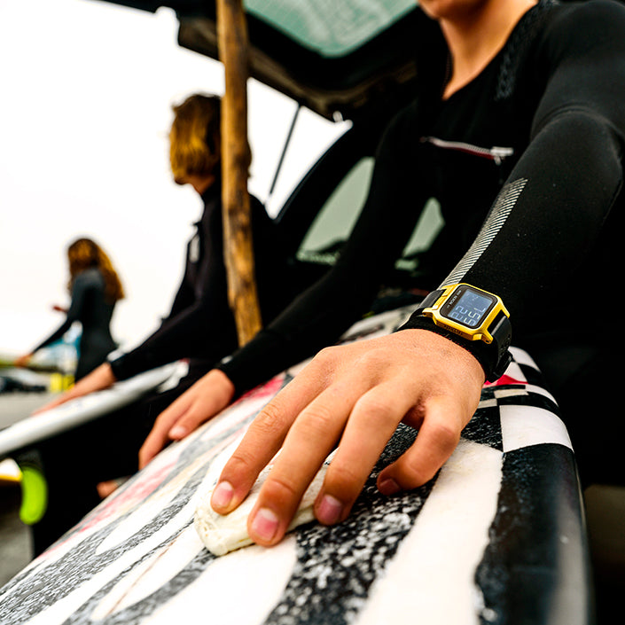 Man wearing Heat watch while waxing surfboard.